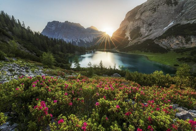 The sun rises behind the Zugpsitze mountain in the Alps.